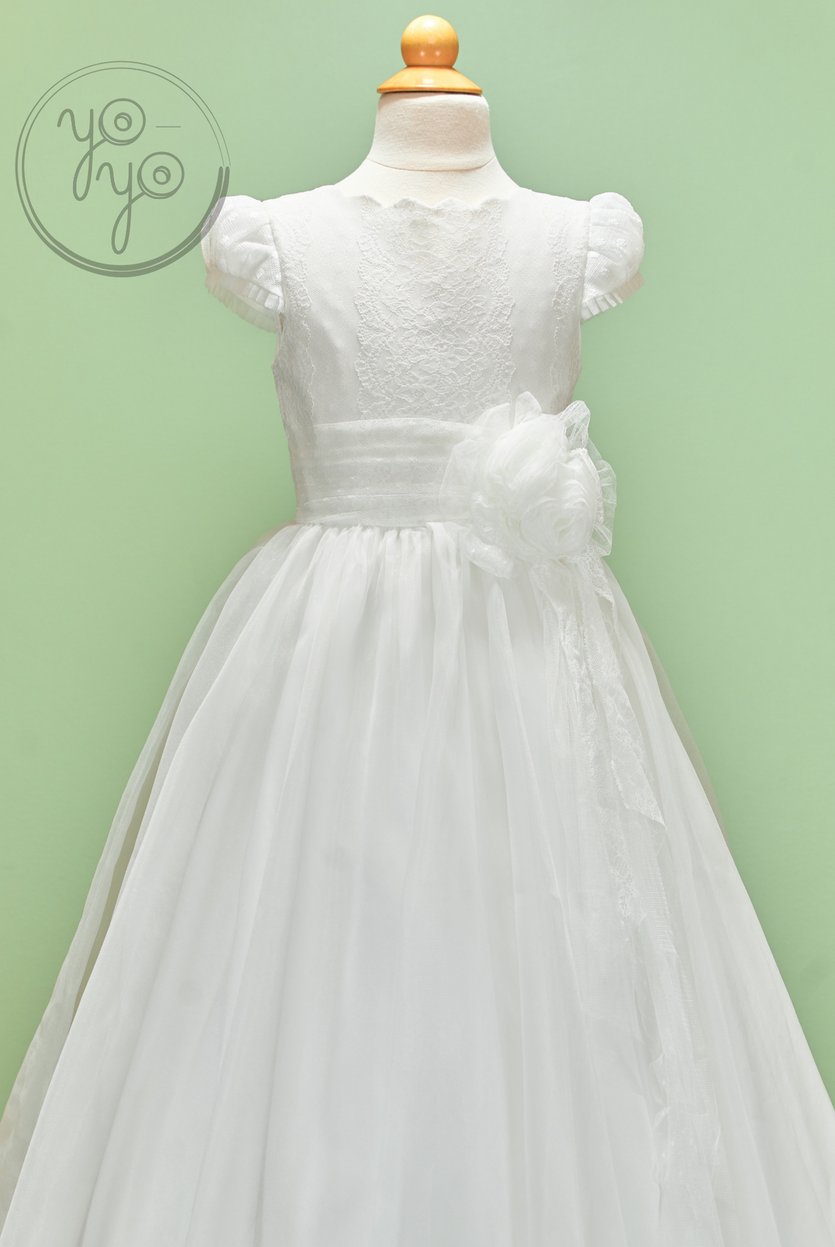 White Iris sleeveless dress in embroidered tulle with a lace bodice, gathered waist, and a large side fabric flower.