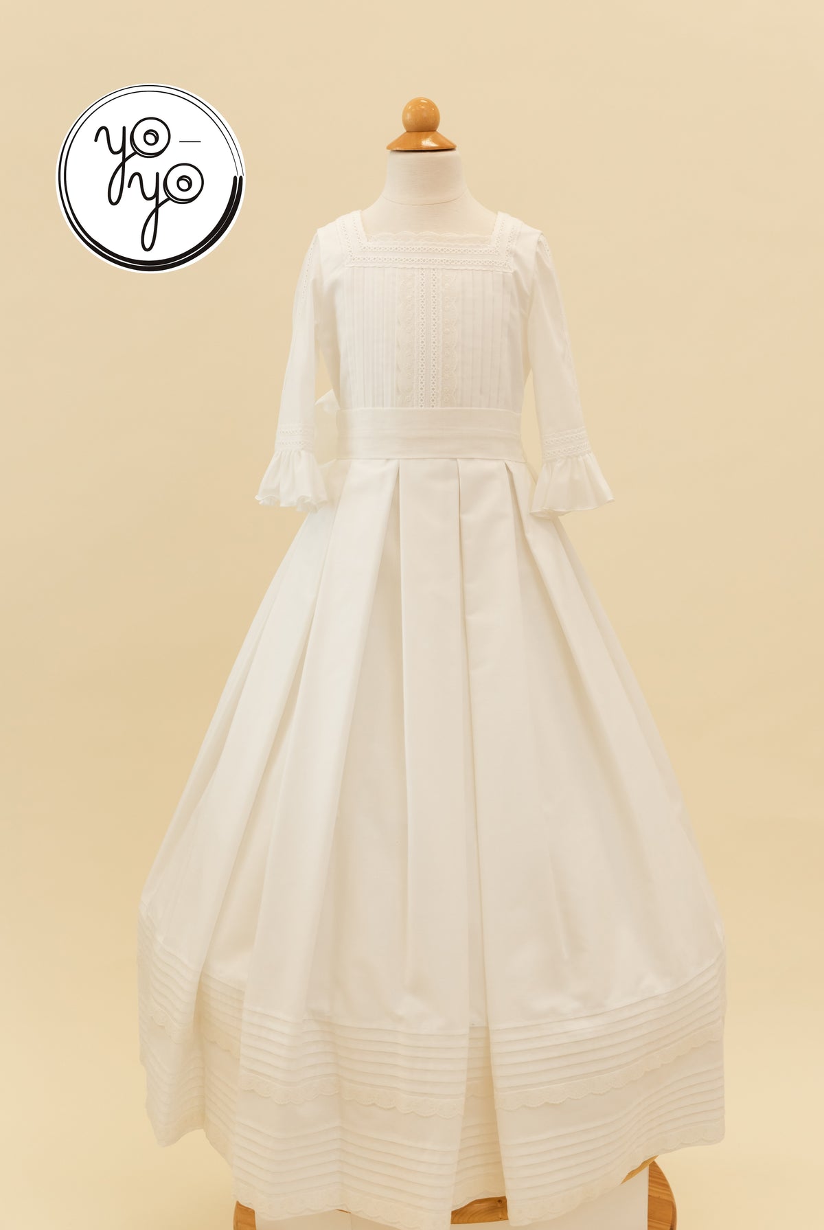 White Claudine A-line dress featuring a square neckline, three-quarter bell sleeves, pintuck detailing, and a pleated skirt.