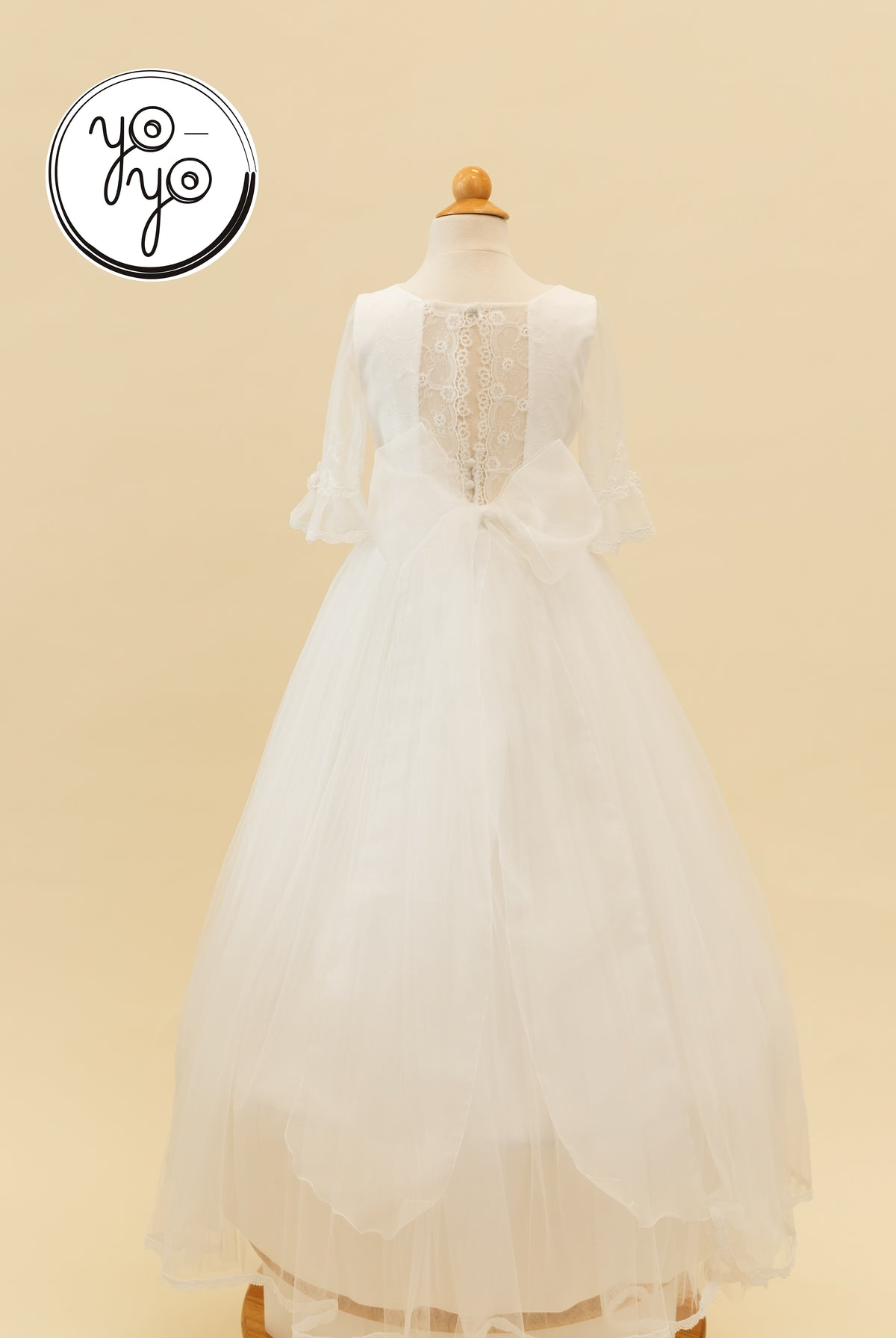 Back view of the white Senna Dress by YoYo Boutique, featuring a lace bodice, sheer sleeves, French tulle skirt, and a large back bow.