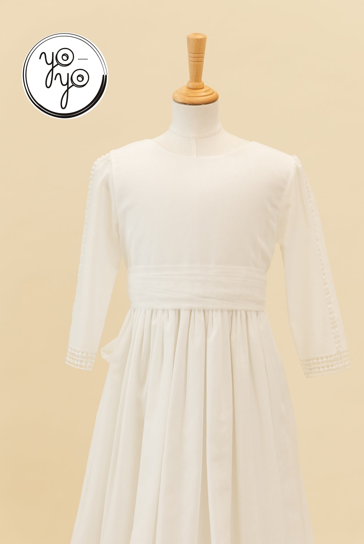 Montserrat Dress in natural white linen with a round neckline, long sleeves with lace cuffs, and a wide waistband.