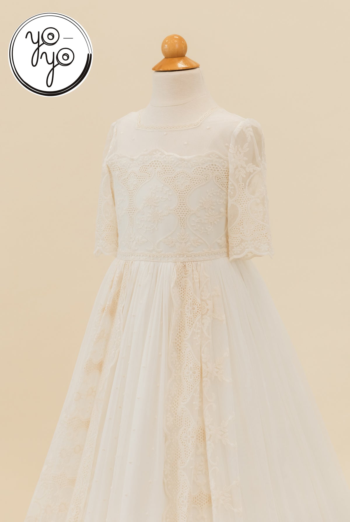 Cream-colored Pino dress with a round neckline, elbow-length lace sleeves, and a boho-style skirt with ornate embroidered French tulle.