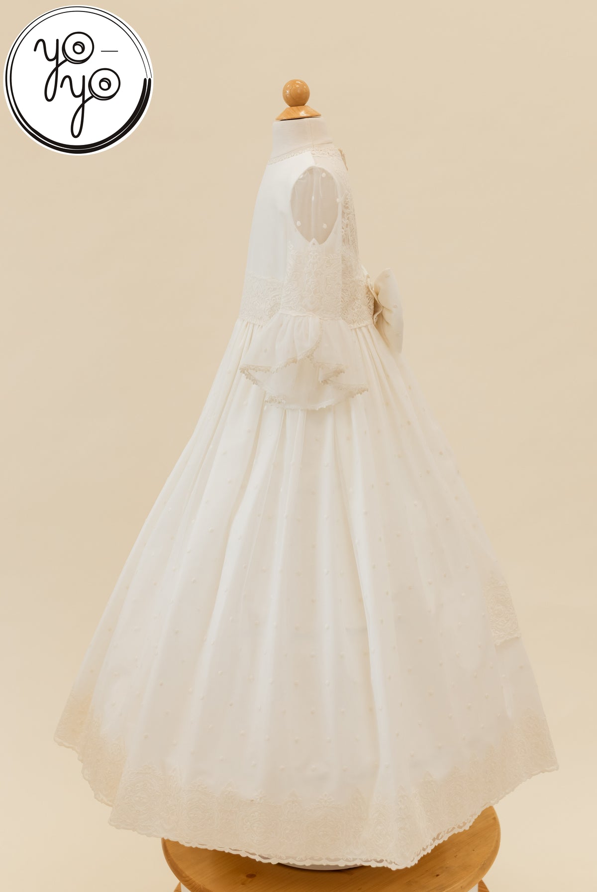 Side view of the white Manon Dress by YoYo Boutique in dotted embroidered tulle, featuring a lace-trimmed bell sleeve and a waist bow.