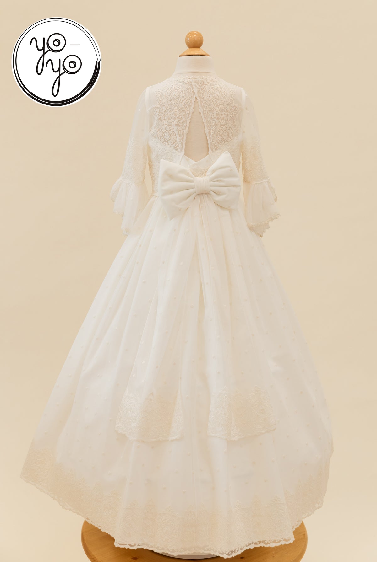 Back view of the white Manon Dress by YoYo Boutique, featuring a lace bodice, ruffled three-quarter sleeves, and a large bow over a tulle skirt.