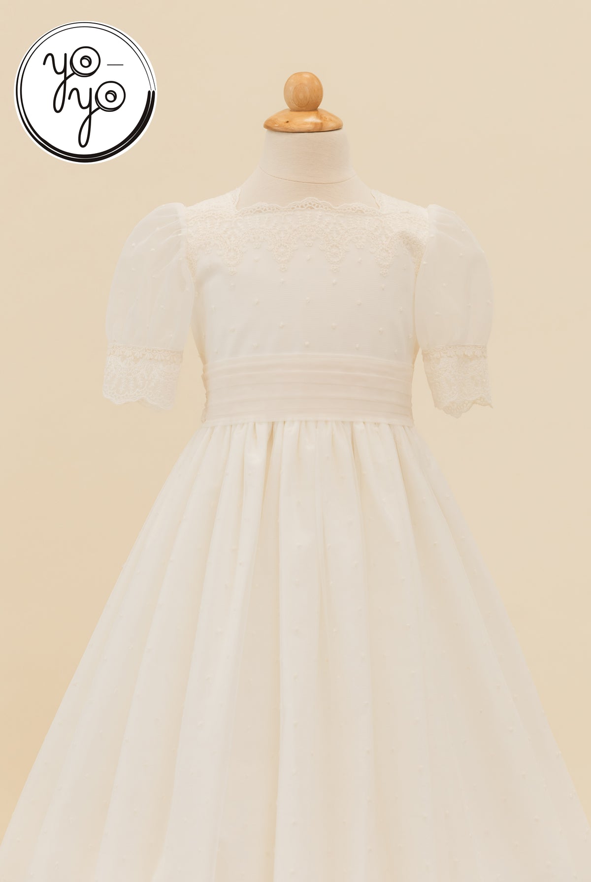 Sophie Dress: Ivory boho First Communion dress on a mannequin featuring short puff sleeves, a lace-trimmed square neckline, and a gathered skirt.