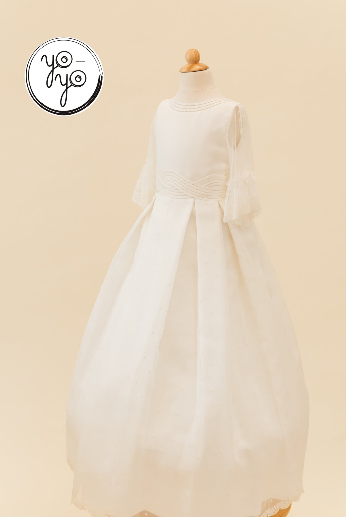 Ceibo Dress by YoYo Boutique: off-white First Communion dress with a high neckline, lace-trimmed French sleeves, and a pleated textured dot skirt.