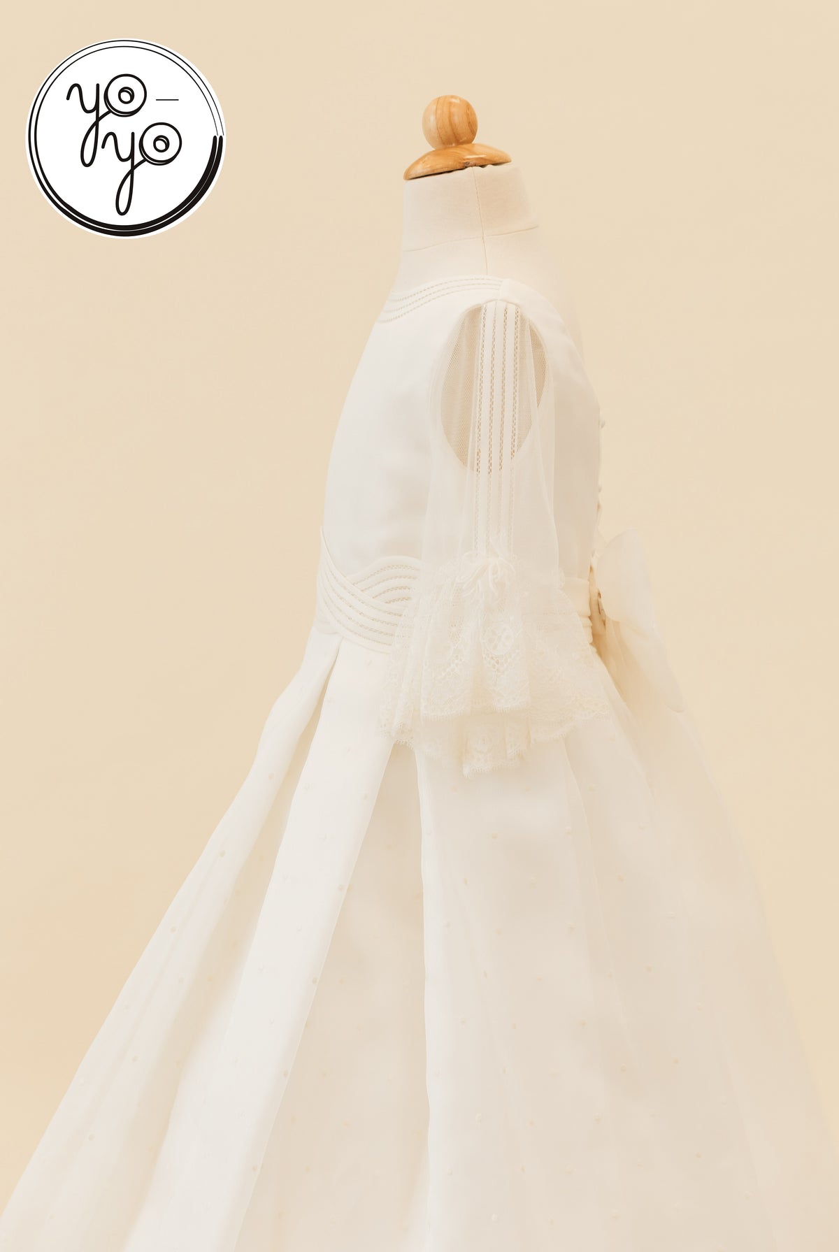 Side view of the off-white Ceibo Dress featuring French sleeves, lace-trimmed edges, a high waistband, and a large back bow.