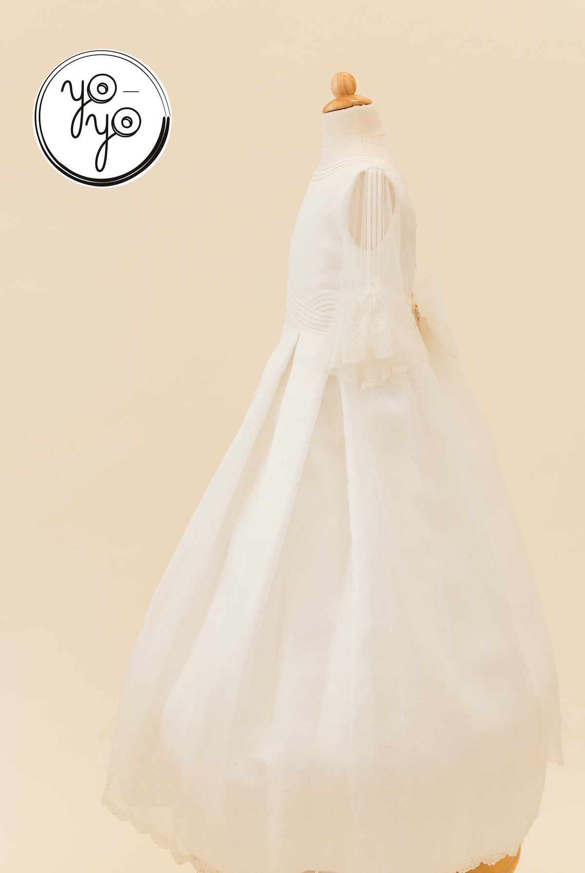 Side view of the white Ceibo Dress by YoYo Boutique, featuring sheer French lace sleeves, a wide waistband, and a back bow.