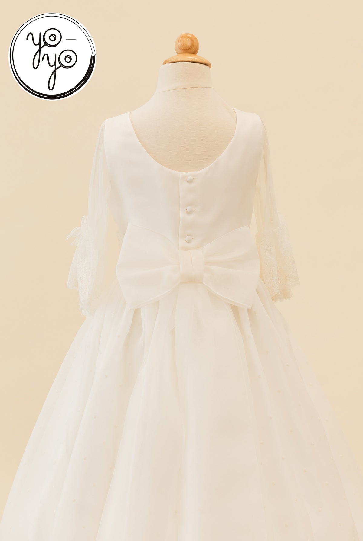 Back view of the off-white Ceibo Dress by YoYo Boutique, featuring French sleeves, a button-up back, and a large waist bow.