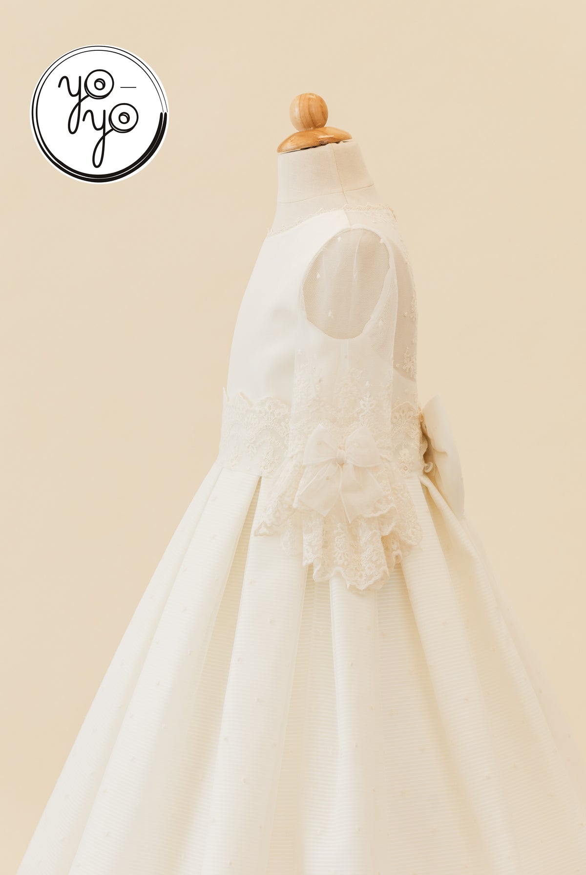 Ivory boho Giselle Deluxe Dress on a mannequin, featuring sheer lace sleeves, a lace waistband, and a back bow.
