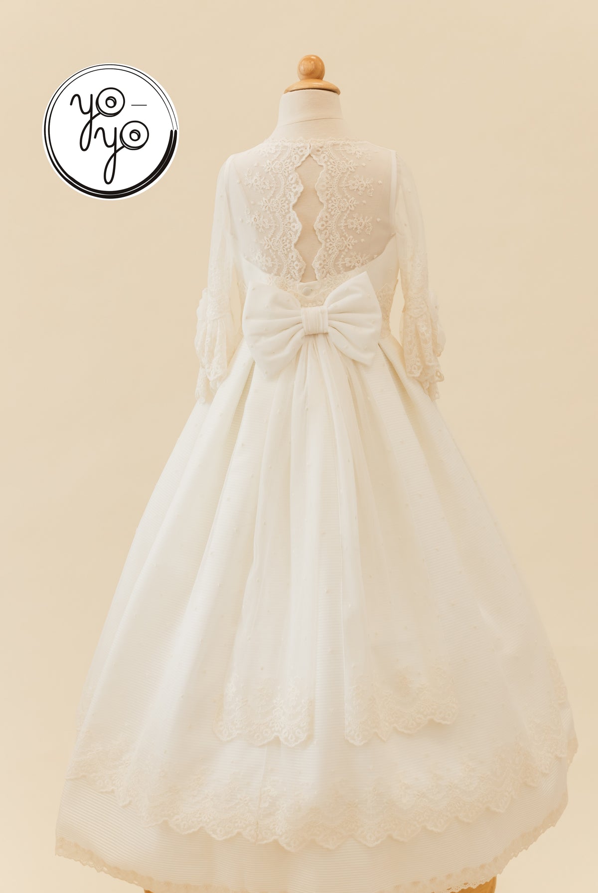 Back view of the white, floor-length Giselle Deluxe boho dress featuring a lace-trimmed bodice, long sleeves, and a large waist bow.