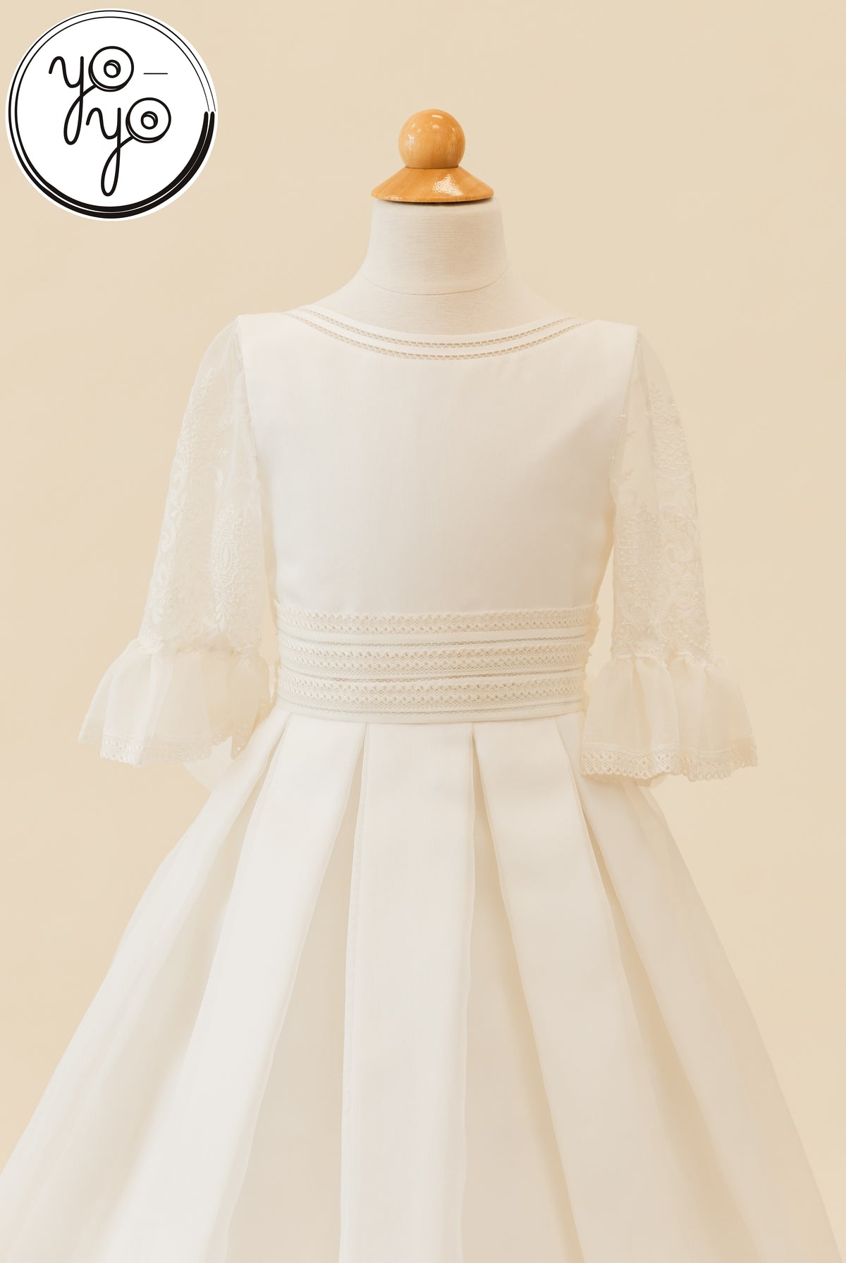 Magnolia Dress in ivory rustic gauze on a mannequin, featuring embroidered lace sleeves, a wide banded waist, and a pleated skirt.