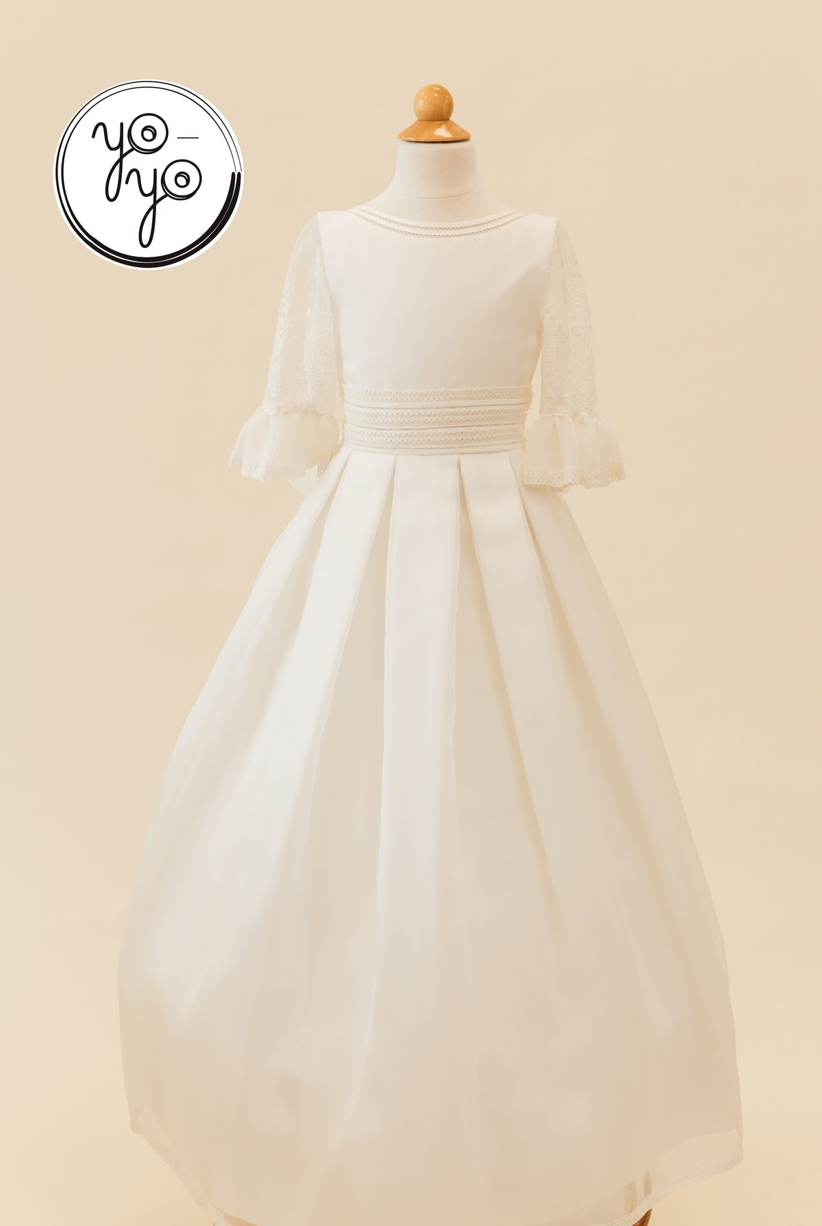Magnolia Dress in white rustic gauze on a mannequin, featuring embroidered lace three-quarter sleeves, a tiered waist, and a floor-length skirt.