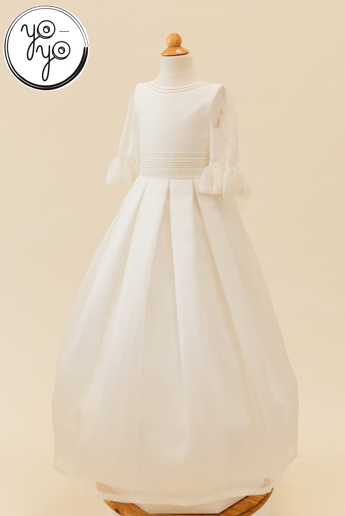 Magnolia Dress on a mannequin: white floor-length gown featuring embroidered lace elbow-length sleeves, a banded waist, and a pleated gauze skirt.