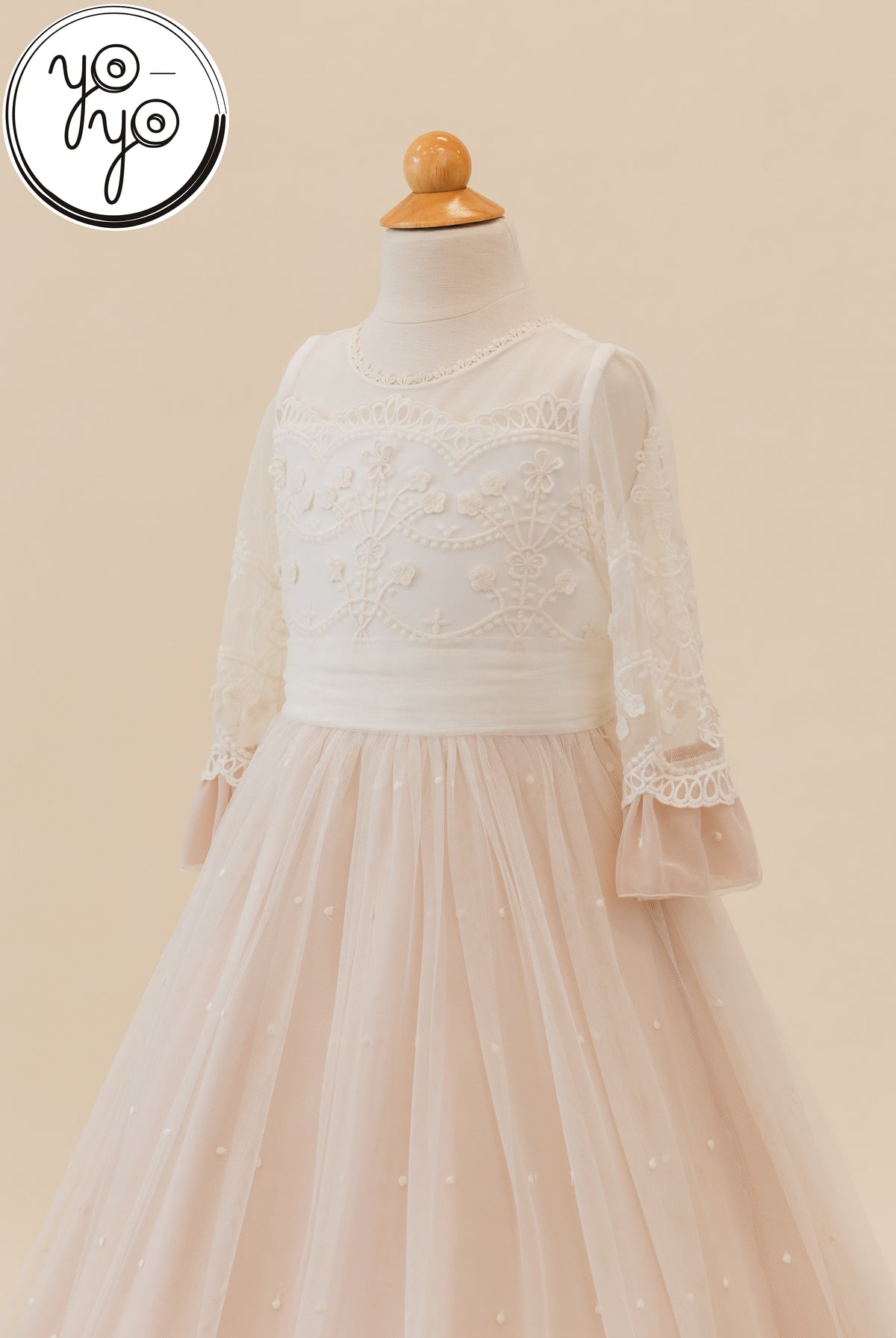 The Lua Dress by YoYo Boutique: a cream First Communion dress featuring a lace-embroidered bodice, sheer sleeves, and a tiered tulle skirt.