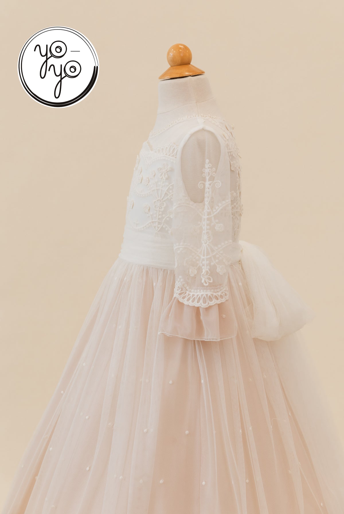 Lua Dress by YoYo Boutique: A cream A-line First Communion dress featuring sheer lace sleeves, an embroidered bodice, and a dusty rose tulle overlay.
