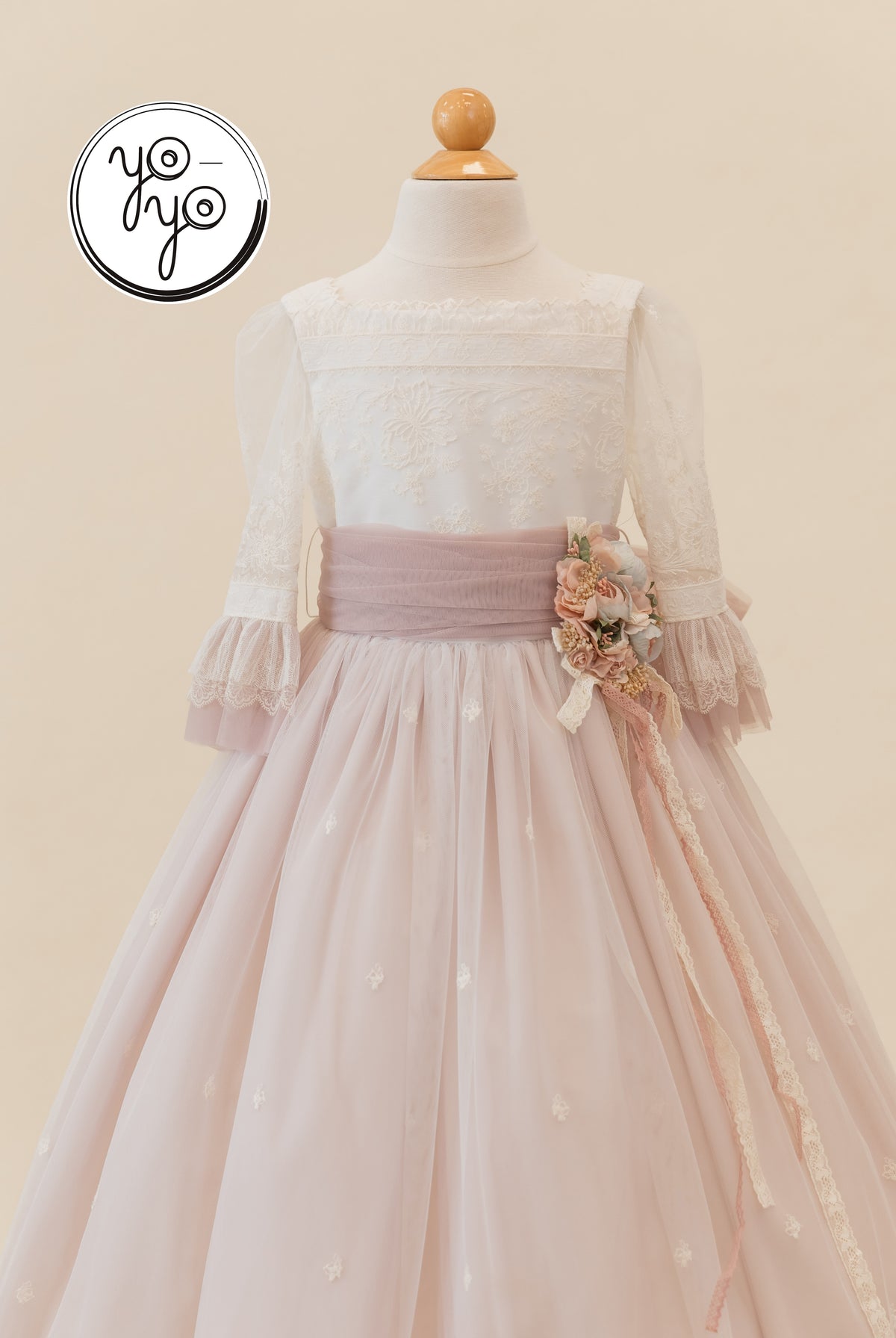 YoYo Boutique Elena Communion gown: ivory embroidered French tulle with sheer three-quarter sleeves, mauve sash, and floral waist.