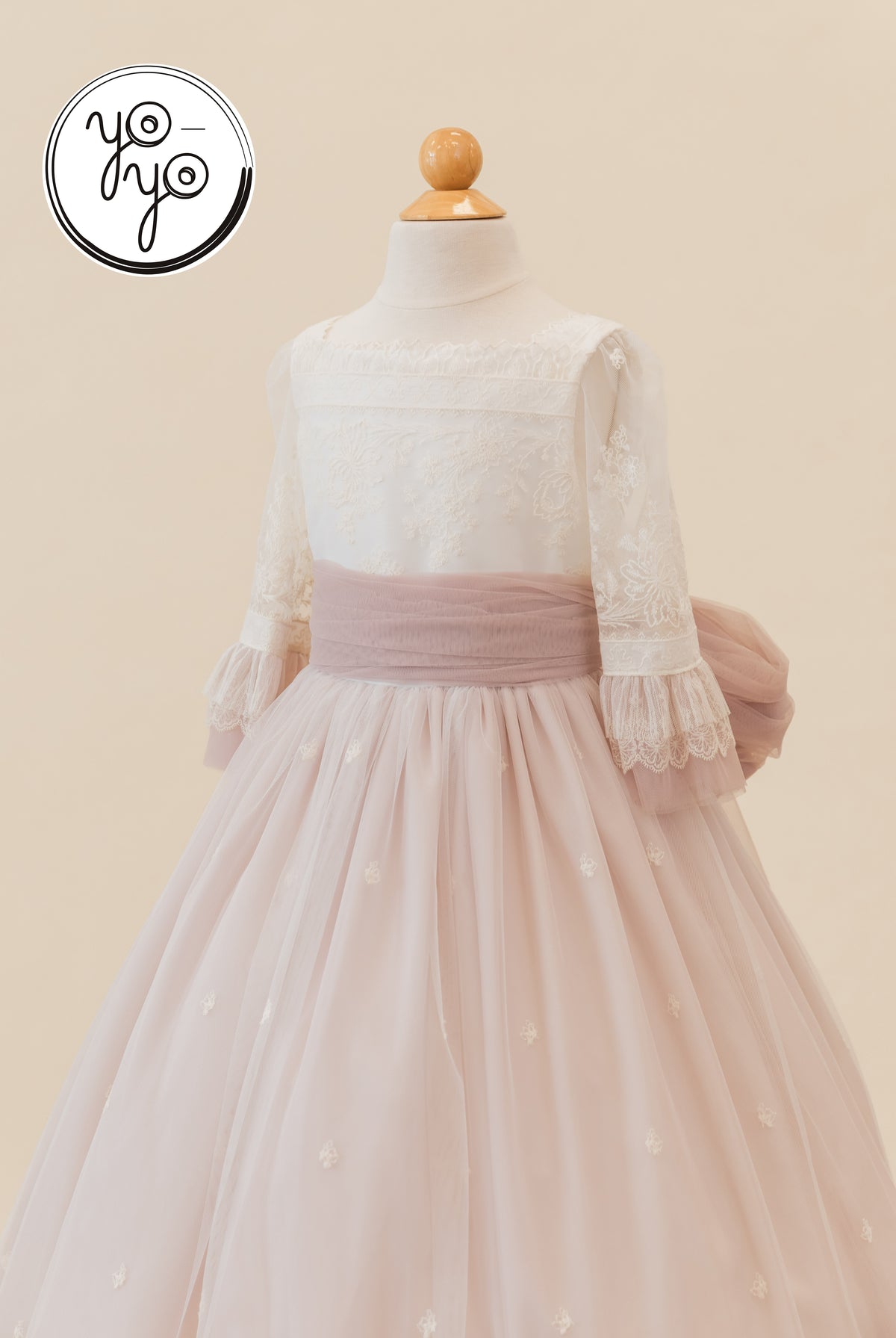 Cream Elena Communion dress with an embroidered French tulle bodice, three-quarter sleeves, dusty rose sash, and a full boho skirt.