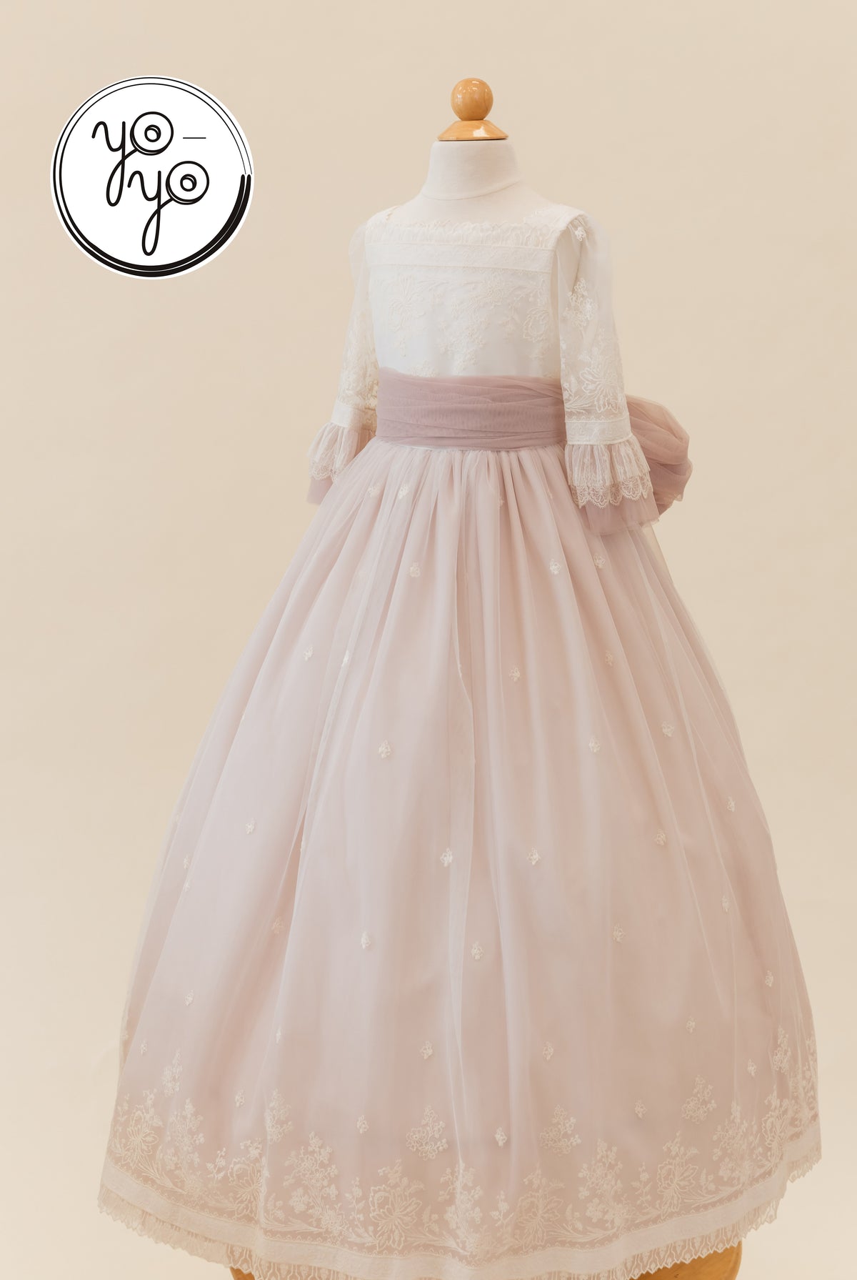 The Elena Dress by YoYo Boutique: a floor-length white lace bodice Communion gown with a mauve sash and an embroidered, tiered tulle skirt.