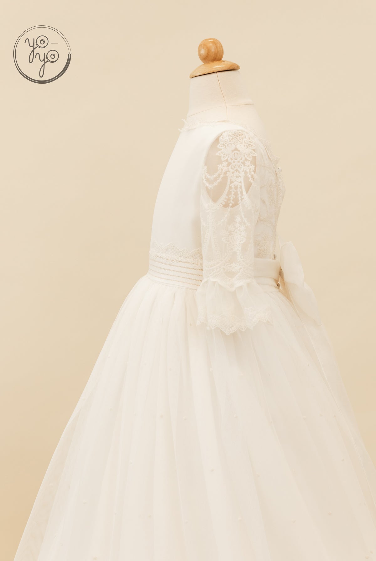 Nerina Dress by YoYo Boutique: off-white boho gown on a mannequin featuring lace sleeves, a textured waistband, and a pearl-accented tulle skirt.