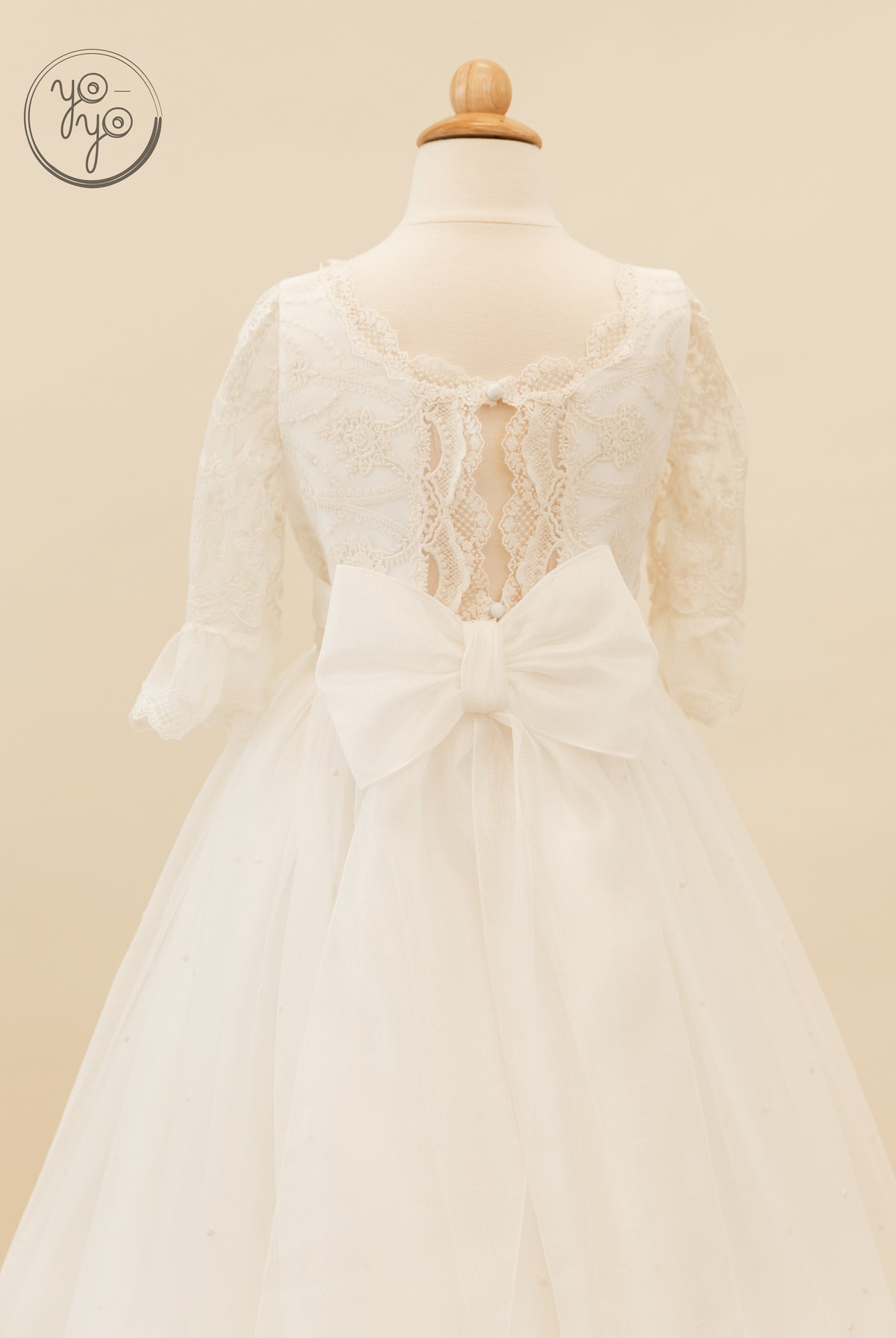 Back view of the white French tulle Nerina Dress with three-quarter lace sleeves, an open back, and a large waist bow.