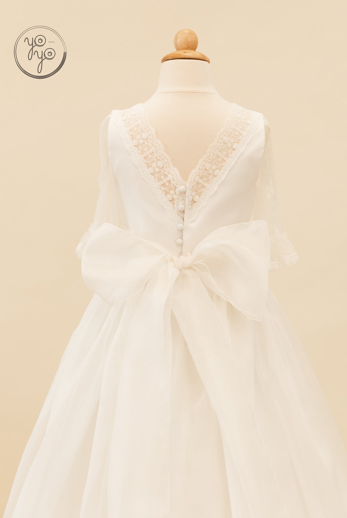 Back view of the YoYo Boutique Jacinto dress, a boho First Communion style featuring sheer sleeves, button detailing, and an organza bow.