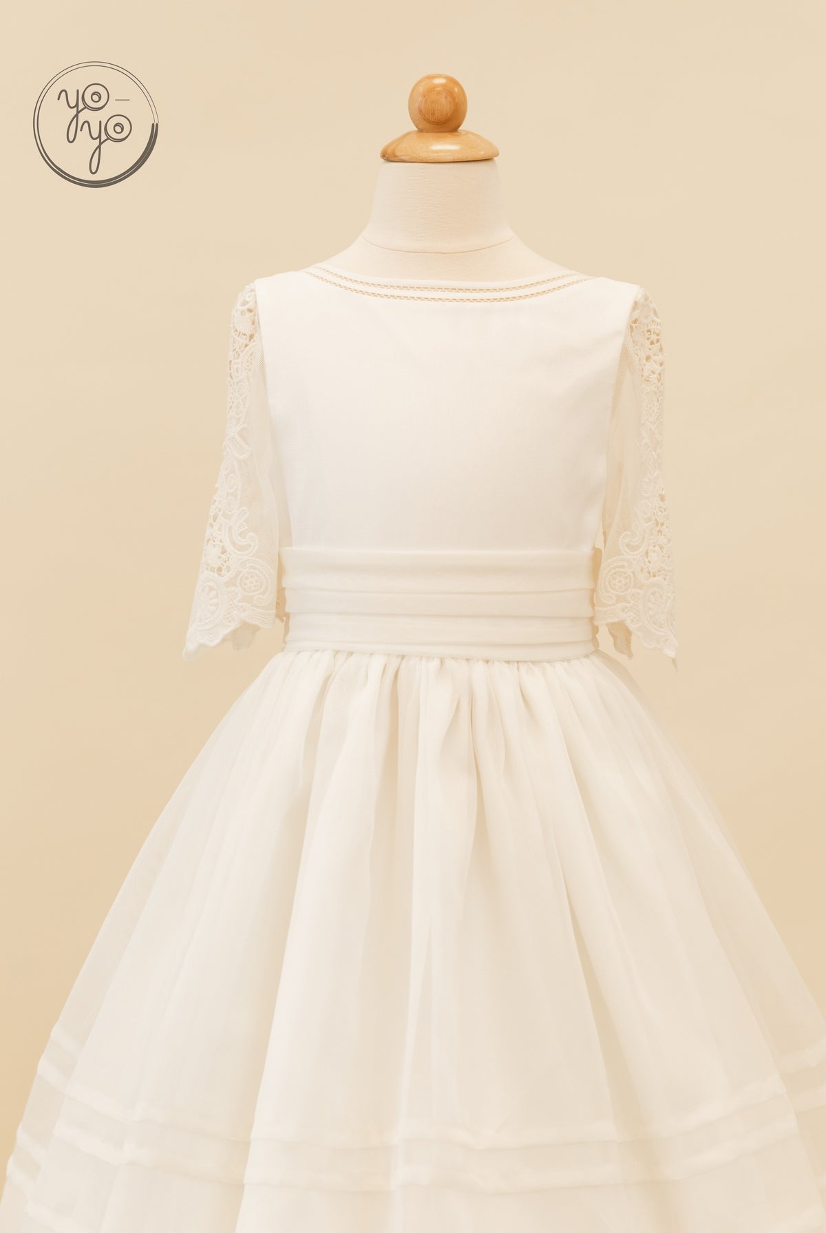 Off-white boho Coral dress on a mannequin featuring a boat neckline, lace elbow-length sleeves, a wide waistband, and a full, layered skirt.