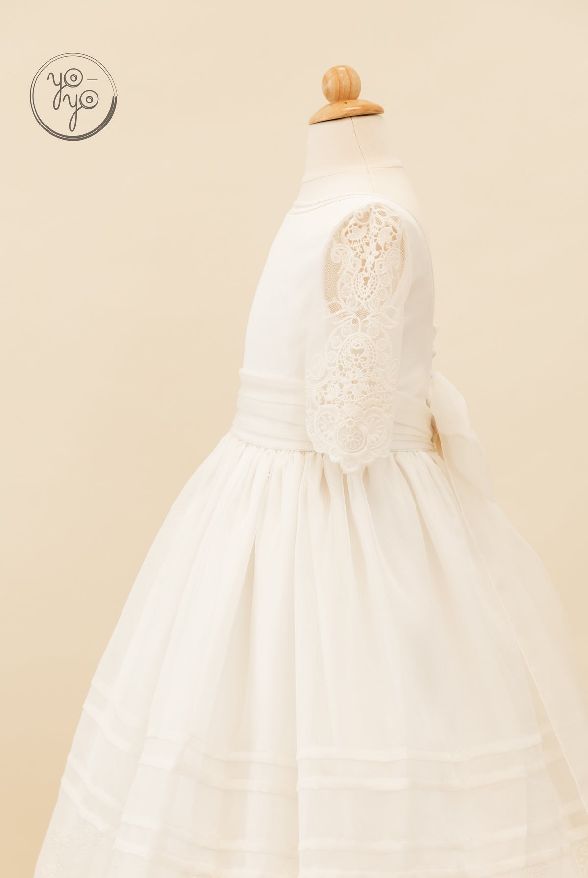 Side view of a white embroidered Coral Dress featuring three-quarter lace sleeves, a wide waistband with a back bow, and a layered tulle skirt.