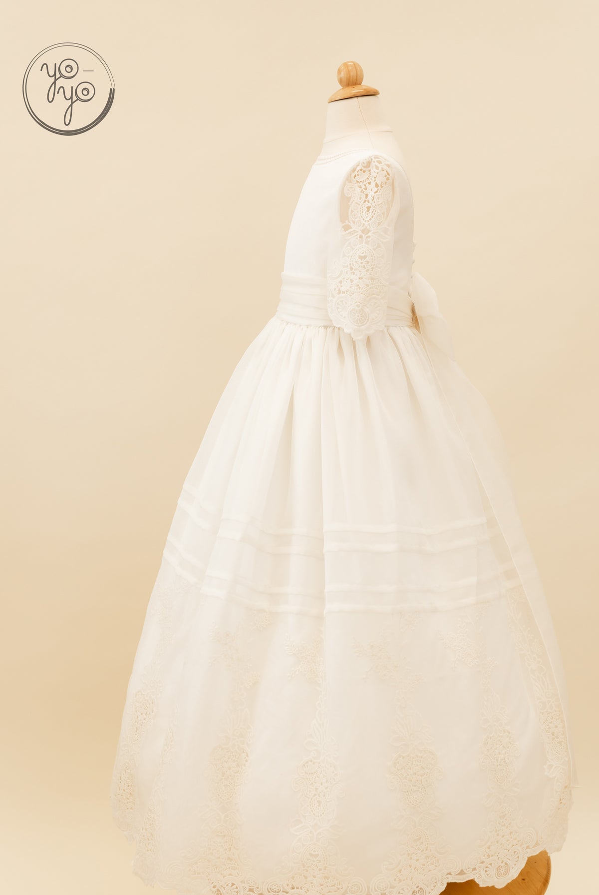YoYo Boutique Coral white floor-length boho First Communion gown with three-quarter lace sleeves and an embroidered floral hem.