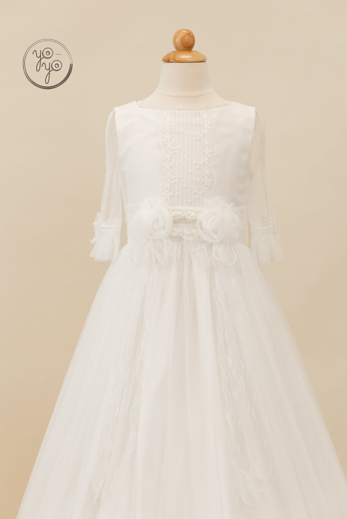 Valeriana dress in white boho style featuring a lace-trimmed bodice, sheer three-quarter sleeves, and two fabric flowers at the waist.
