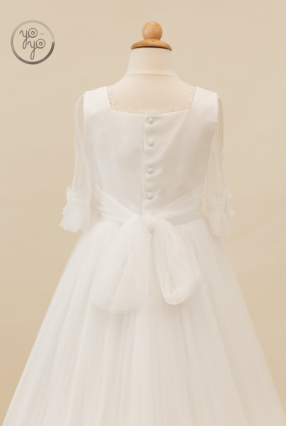 Back view of the Valeriana Dress by YoYo Boutique: square neckline, sheer 3/4 sleeves, buttoned bodice, and a large waist bow.