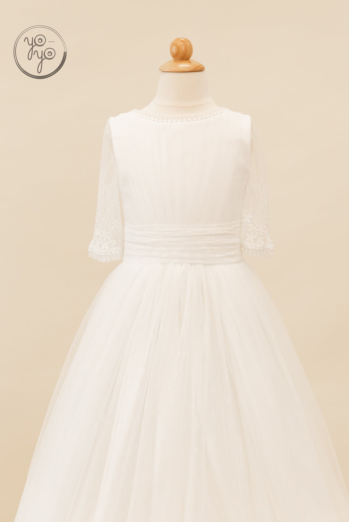Hibisco Dress by YoYo Boutique: a white First Communion dress featuring a beaded neckline, sheer embroidered sleeves, and a layered tulle skirt.