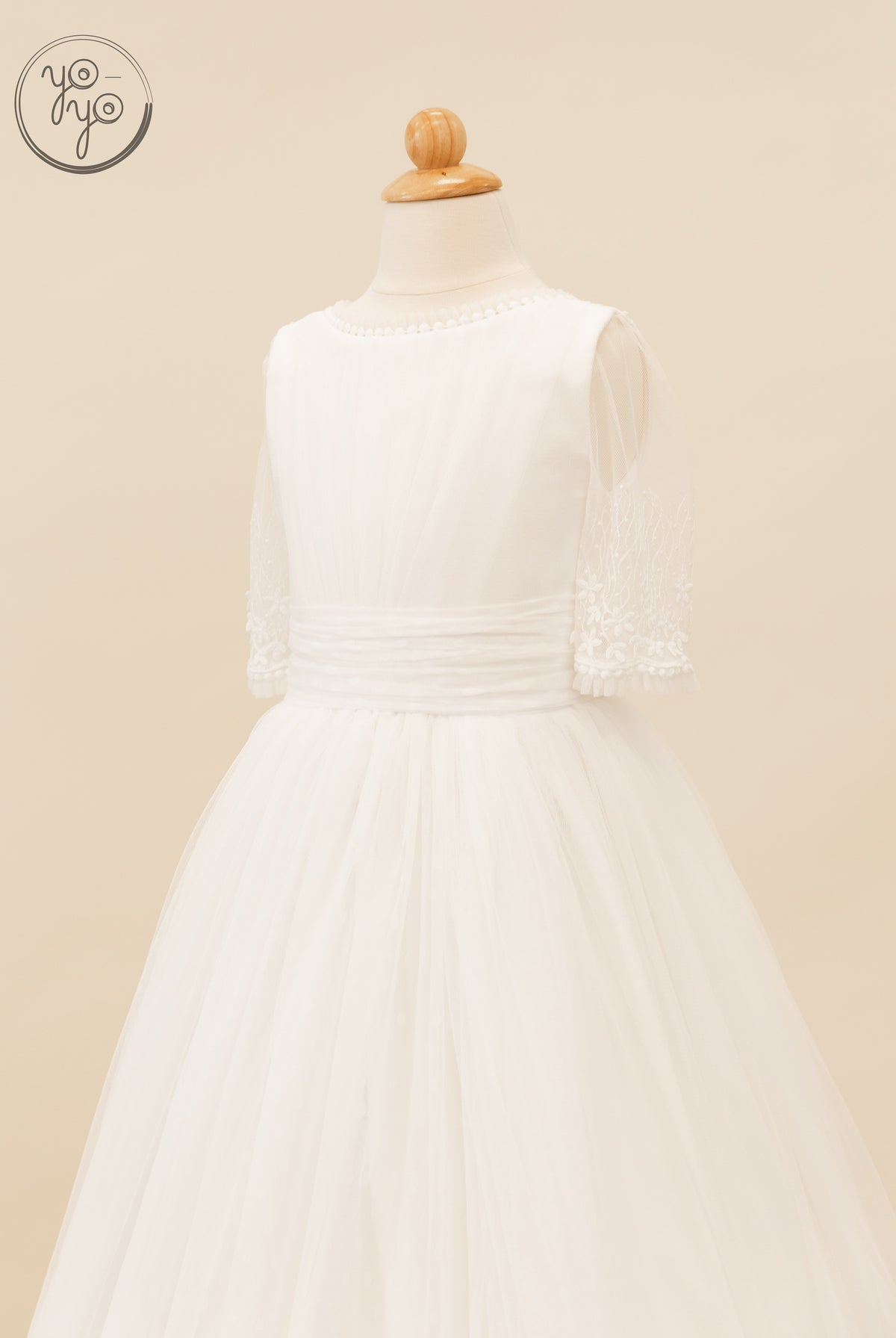 Hibisco Dress by YoYo Boutique: a white A-line First Communion dress with a rounded neckline, sheer French tulle sleeves, and a waistband.