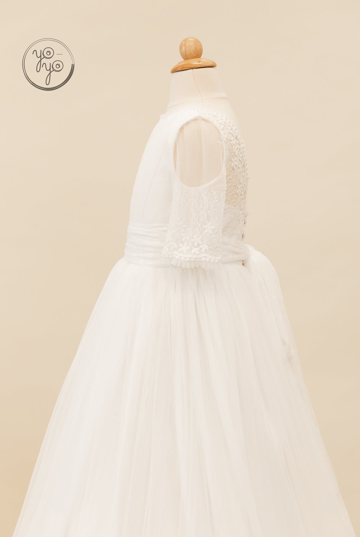 Side view of the white Hibisco Dress with an embroidered lace bodice, sheer cold-shoulder sleeves, and a full French tulle skirt.