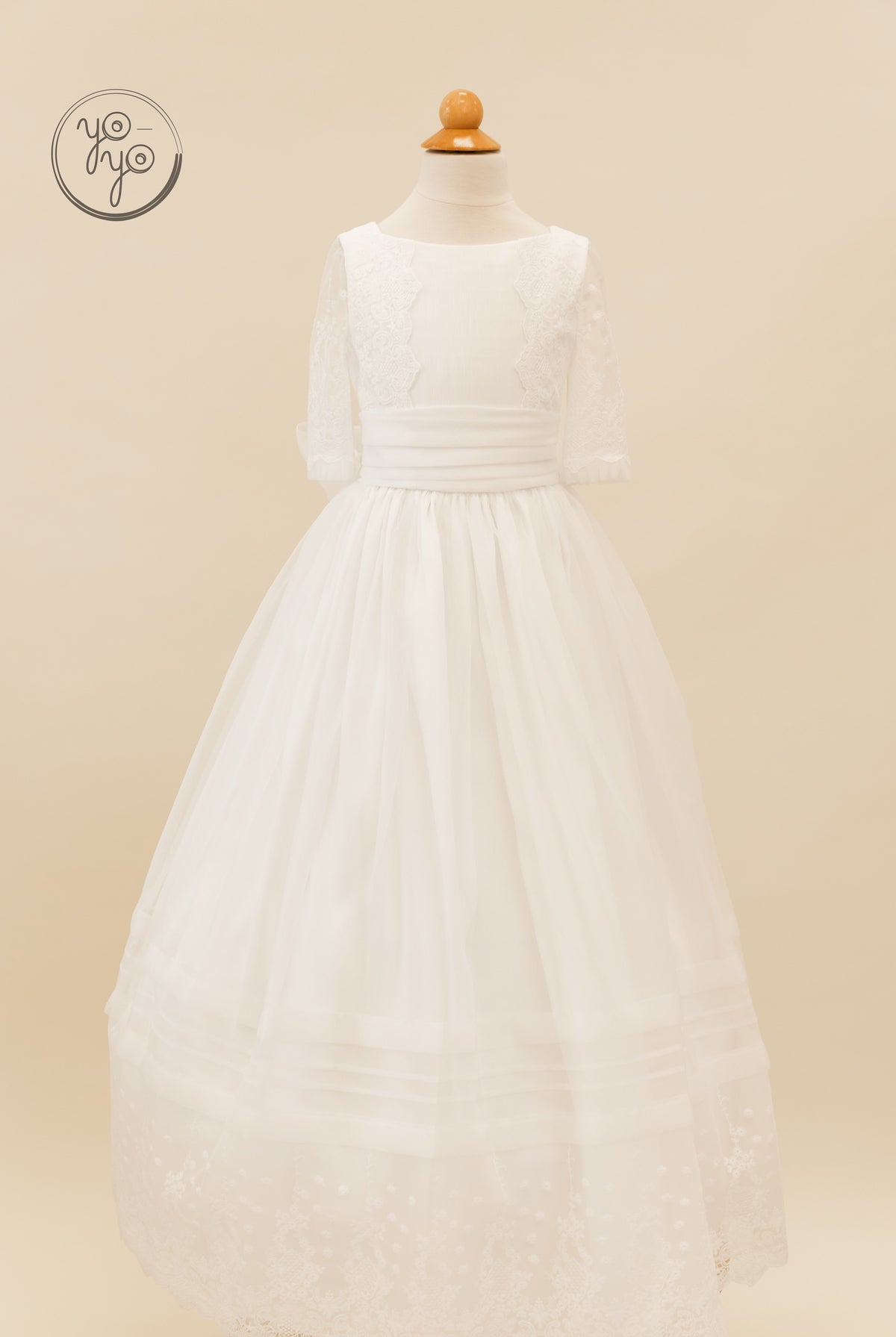 Gladiola Dress on a form: white lace organza dress with three-quarter sleeves, wide waistband, and a tulle skirt with a lace-trimmed hem.