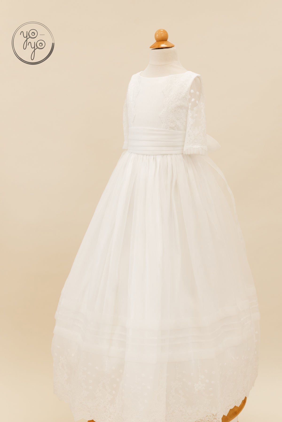 YoYo Boutique Gladiola dress: white lace organza, three-quarter sleeves, wide waistband, and a full-length sheer scalloped hem.