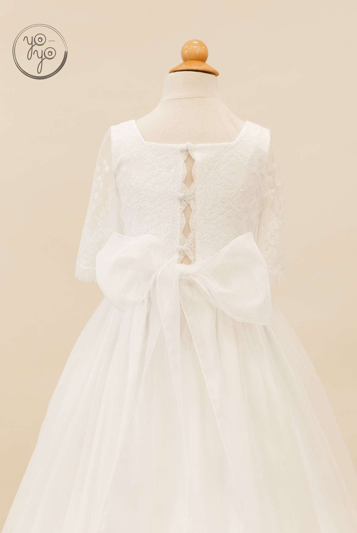 Back view of the Gladiola dress, featuring boho lace organza, three-quarter sleeves, an open back, button closures, and a waist bow.