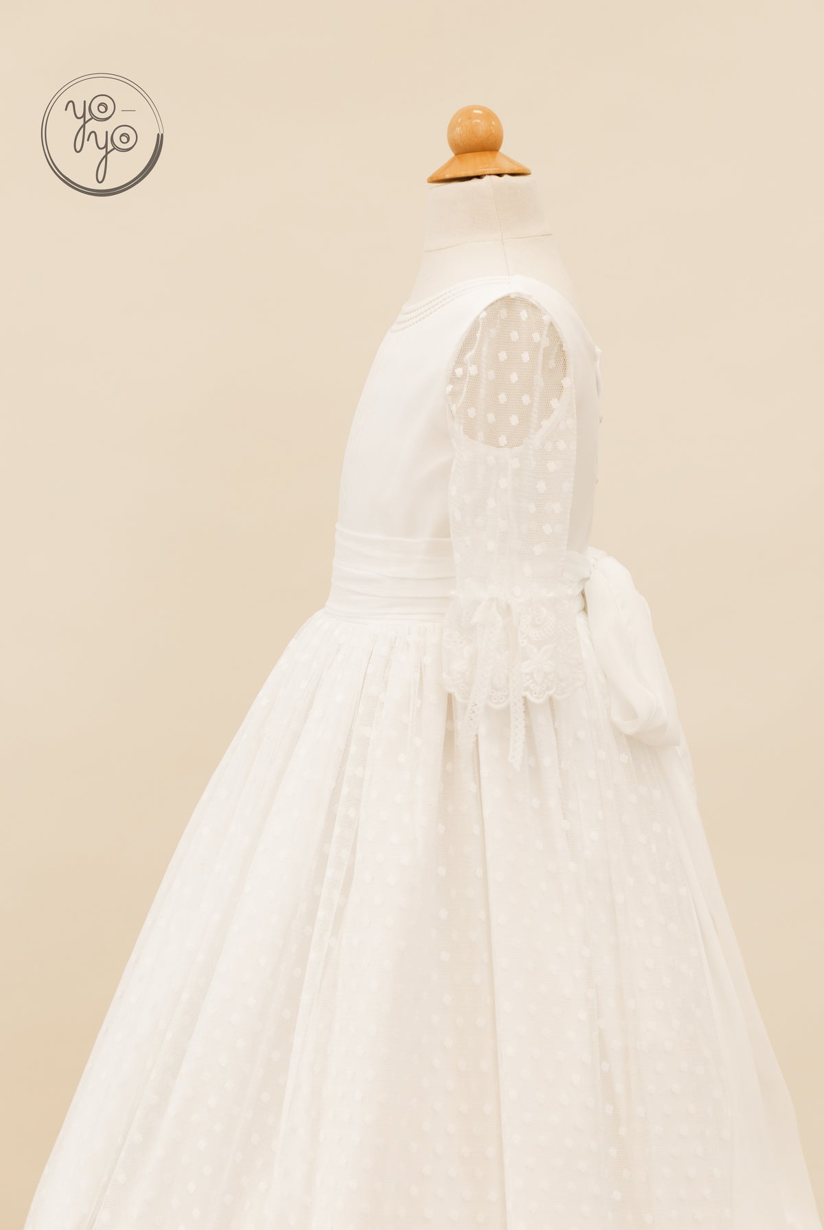 Side view of the white boho Cassia Dress, featuring swiss dot tulle, sheer three-quarter sleeves, and a large back waist bow.