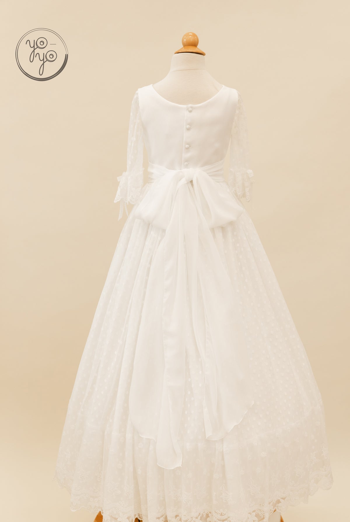 Back view of the YoYo Boutique Cassia dress featuring a button-up bodice, lace sleeves, waist bow, and Swiss dot skirt.