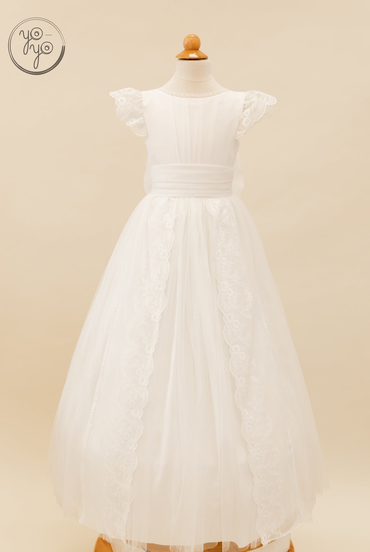 Mannequin wearing a white boho Buganvilla dress featuring a wide waistband, ruffled lace sleeves, and vertical lace panels on the skirt.