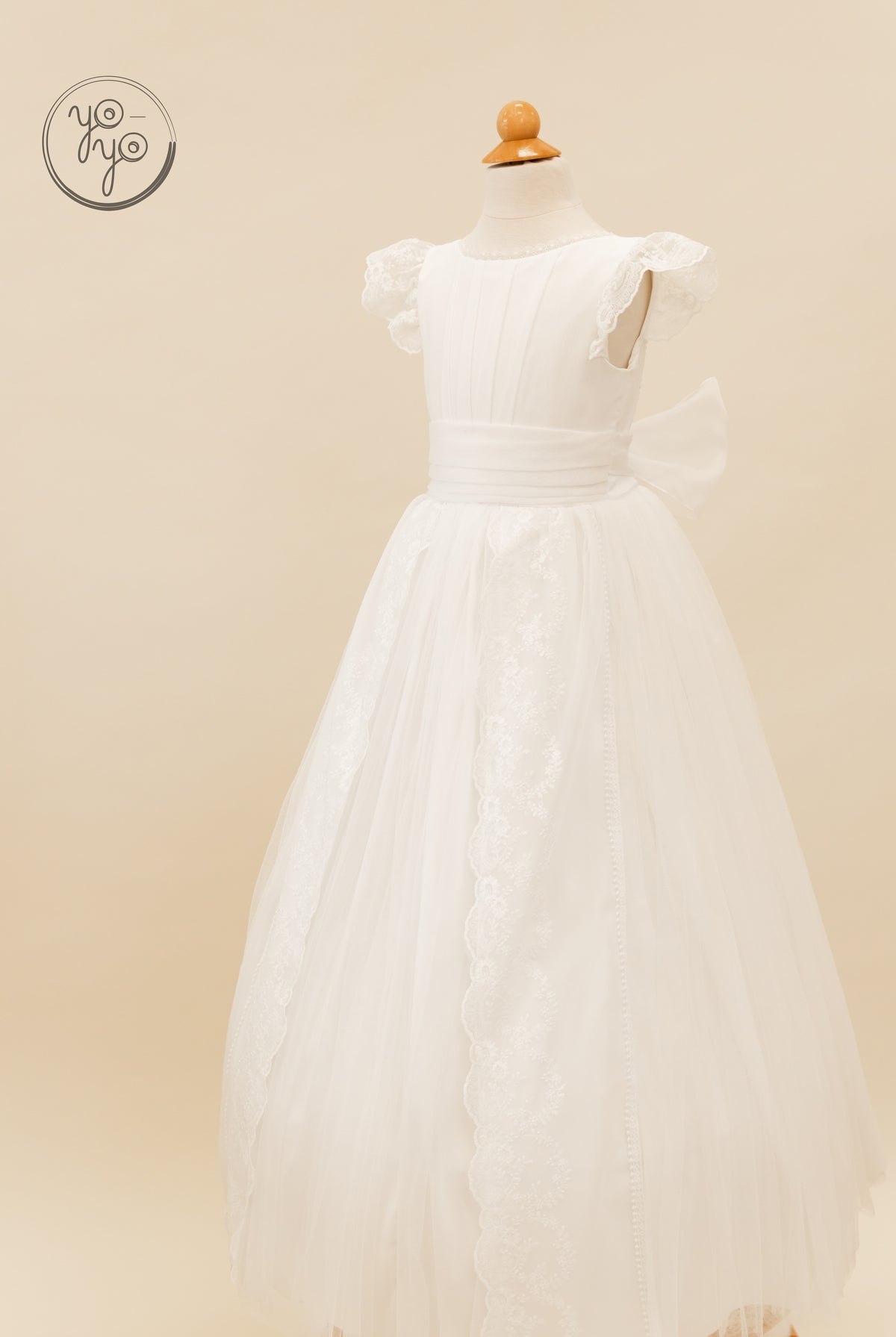 White floor-length boho Buganvilla Dress by YoYo Boutique with cap sleeves, lace trim, and a large back waist bow.