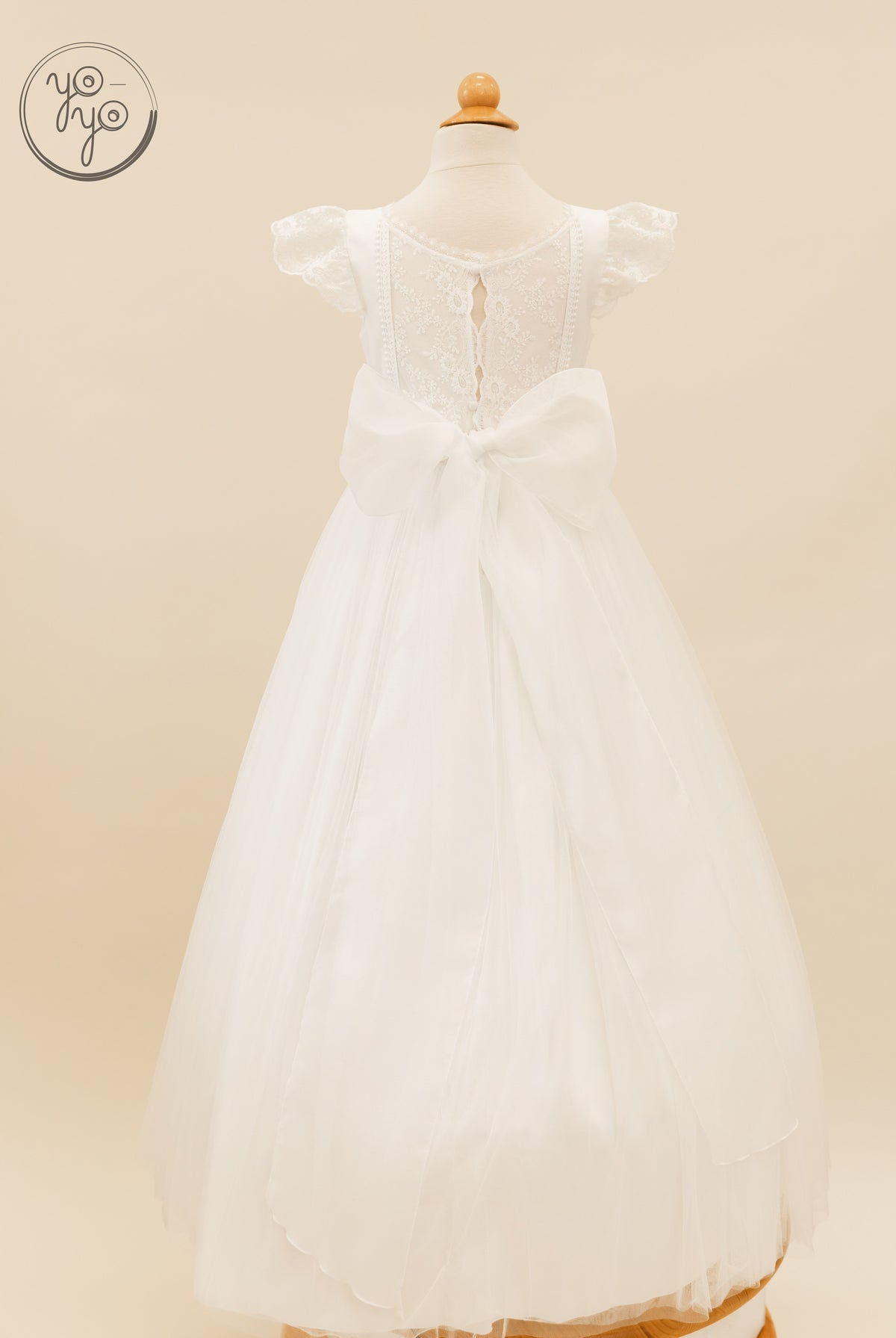 Back view of the white lace Buganvilla Dress featuring a cap-sleeved bodice, large waist bow, and full tulle skirt.