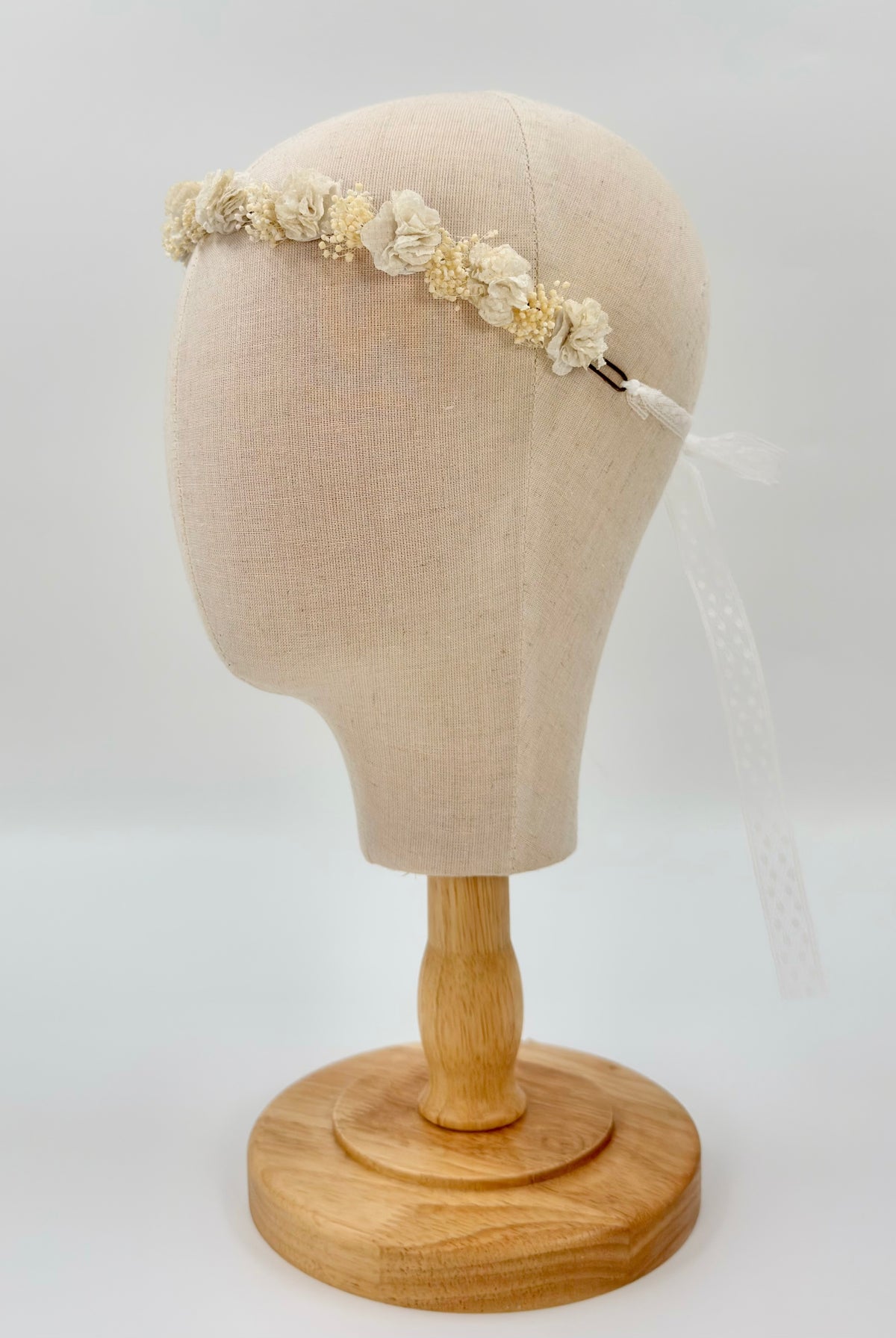 YoYo Boutique off-white flower headpiece on a mannequin head with a trailing sheer ribbon.